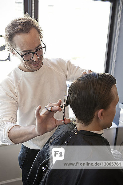 Friseur schneidet Männerhaare mit einer Schere im Friseursalon