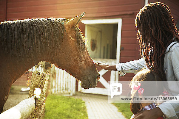 Lehrerin mit Mädchen streichelt Pferd  während sie auf der Ranch steht