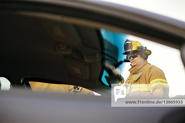 Feuerwehrmann schaut weg  während er am Auto steht