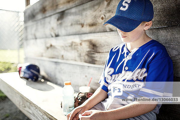 Sad boy relaxing while sitting in dugout