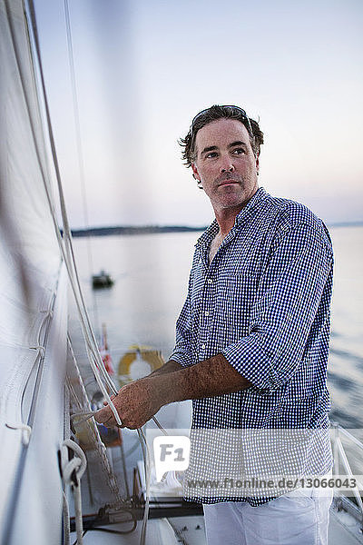 Confident man looking away while standing at yacht