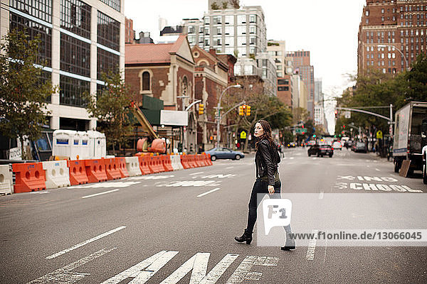 Frau in voller Länge beim Überqueren der Straße in der Stadt