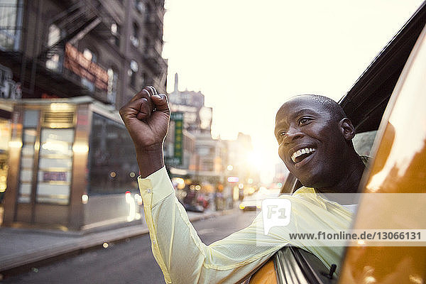 Cheerful man peeking from taxi during sunset