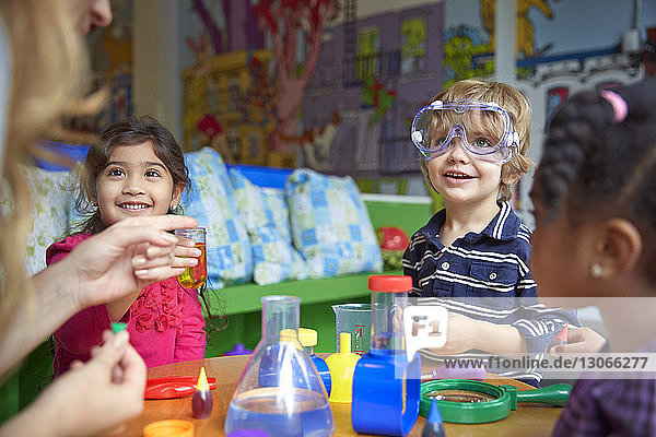 Glückliche Kinder machen wissenschaftliche Experimente am Tisch in der Vorschule