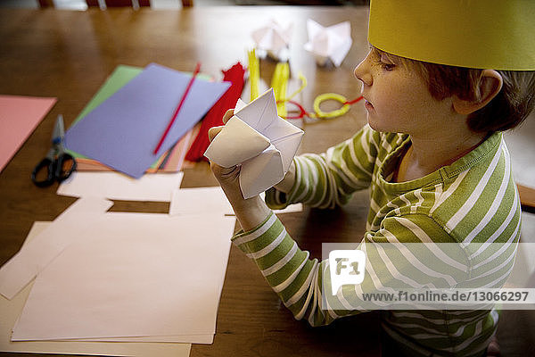 Schrägaufnahme eines Jungen  der Origami-Wahrsager bei Tisch macht