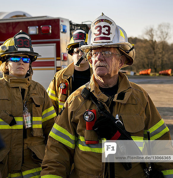 Feuerwehrmann schaut weg  während er mit Kollegen in der Feuerwache steht