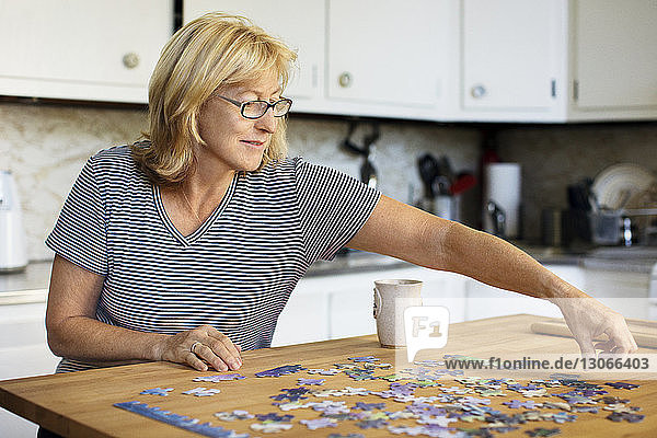 Frau spielt Puzzle am heimischen Tisch