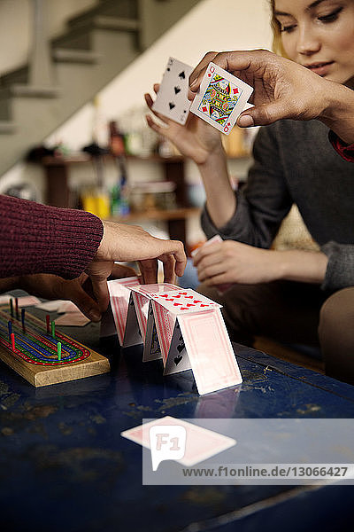 Friends making house of cards at table in living room