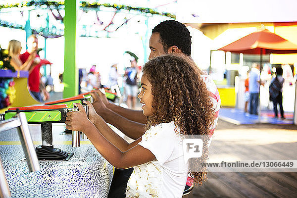 Vater und Tochter spielen mit der Wasserpistole im Vergnügungspark