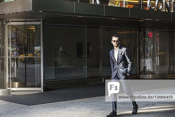Businessman walking on street by in city against clear sky