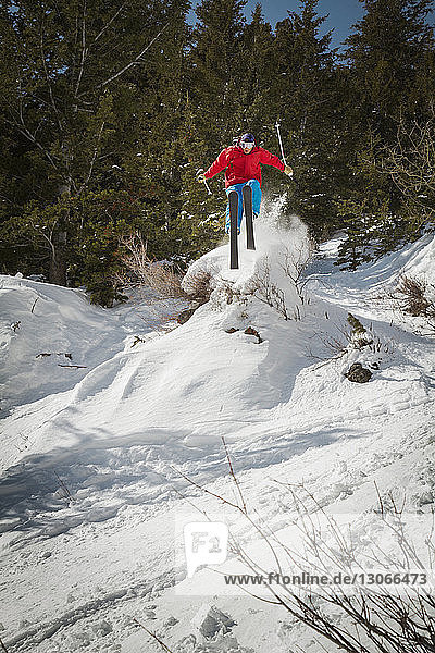 Mann springt beim Skifahren auf schneebedecktem Feld