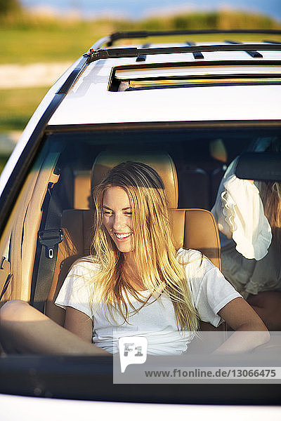 Lächelnde Frau schaut weg  während sie im Auto sitzt