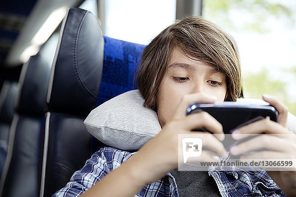 Close-up of boy using mobile phone while sitting in bus