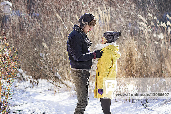 Side view of couple standing on snow covered field