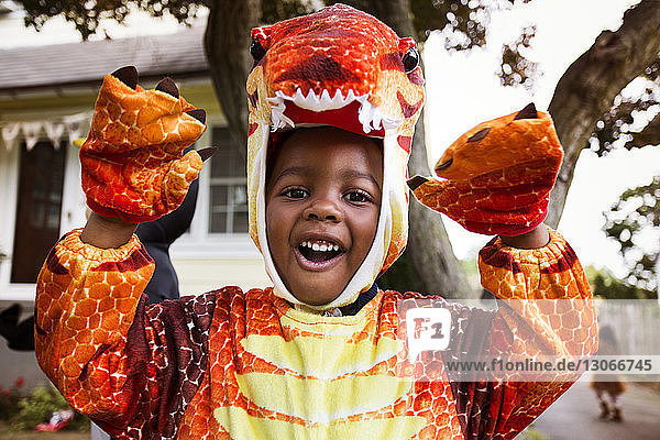 Portrait of happy boy in Halloween costume depicting dinosaur