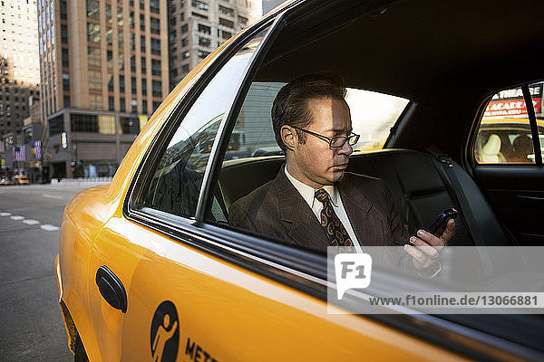 Businessman using mobile phone in taxi