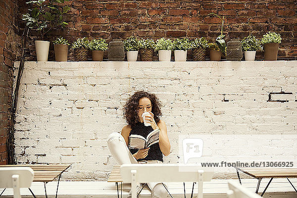 Frau liest Buch beim Kaffeetrinken im Straßencafé