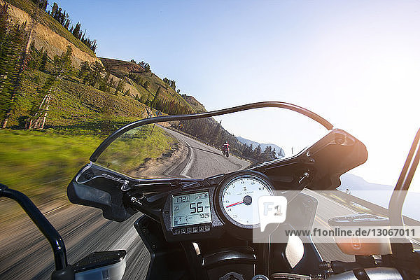 Beschnittenes Bild eines Motorrads  das sich auf einer Bergstraße vor klarem Himmel bewegt