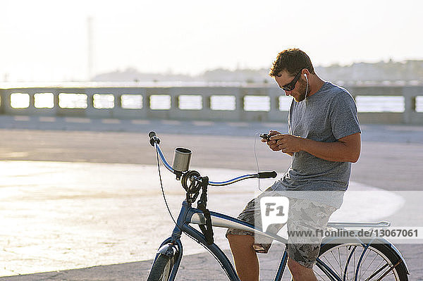 Mann benutzt Smartphone  während er auf dem Fahrrad sitzt