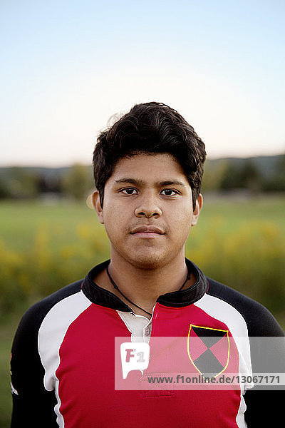 Portrait of rugby player standing on field against sky