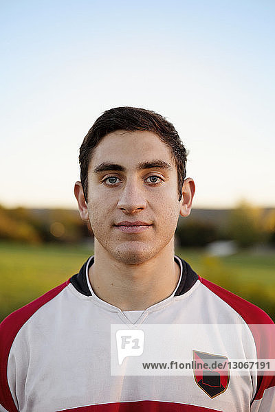 Portrait of confident rugby player on field against clear sky