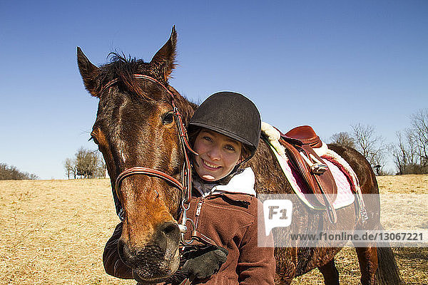 Bildnis eines glücklichen Jungen mit Pferd auf einem Feld vor klarem Himmel stehend