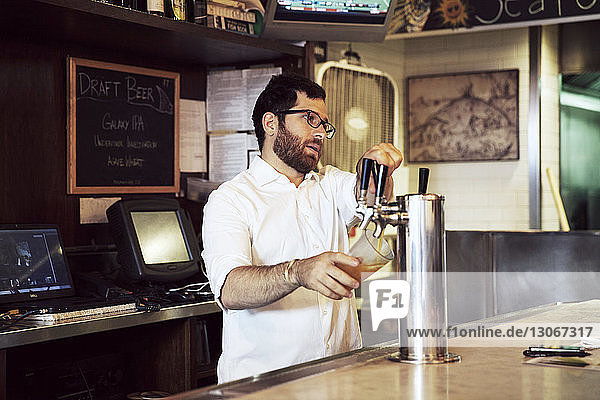 Mann gießt Bier aus dem Zapfhahn  während er im Restaurant steht