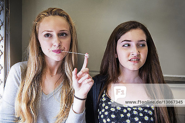 Teenager-Mädchen spielt mit Kaugummi  während sie mit einem Freund im Flur der High School steht