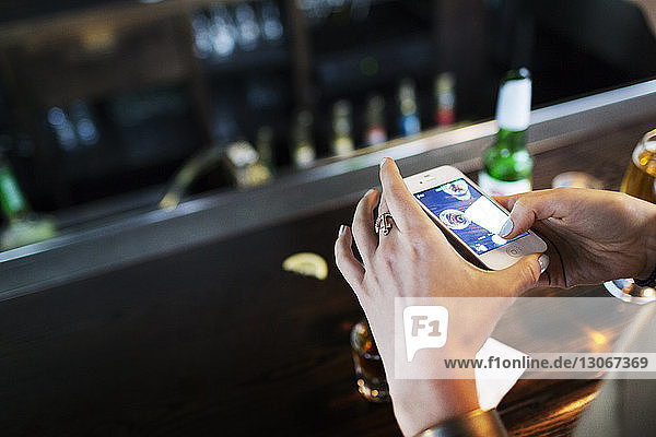 Hochwinkelaufnahme einer Frau  die Alkohol auf einem Tisch in einer Bar fotografiert