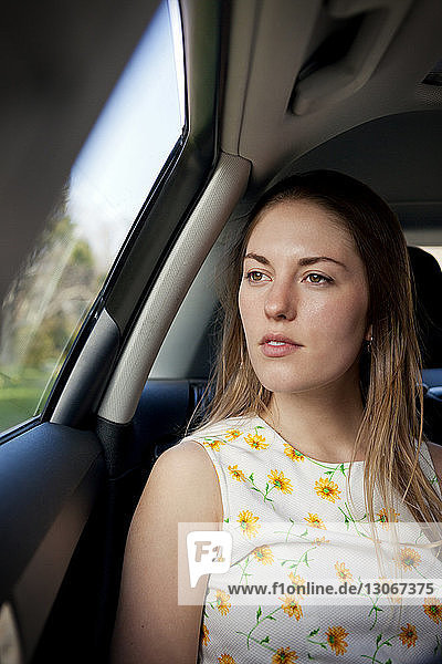 Nachdenkliche Frau schaut weg  während sie im Auto sitzt