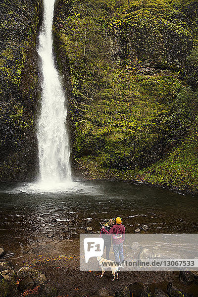 Rückansicht eines Paares mit einem Wasserfall mit Hundeblick