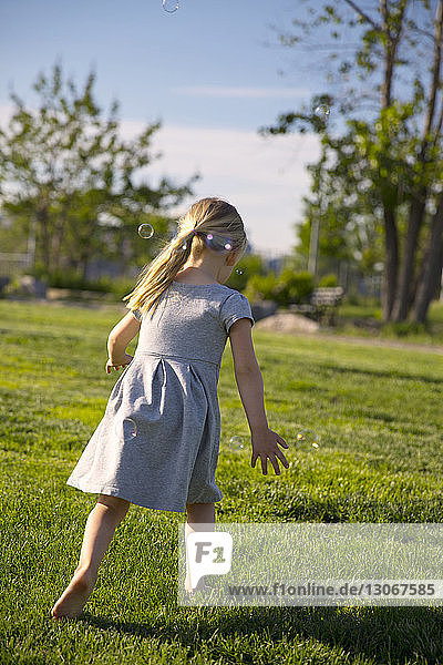 Rear view of girl walking on field at park