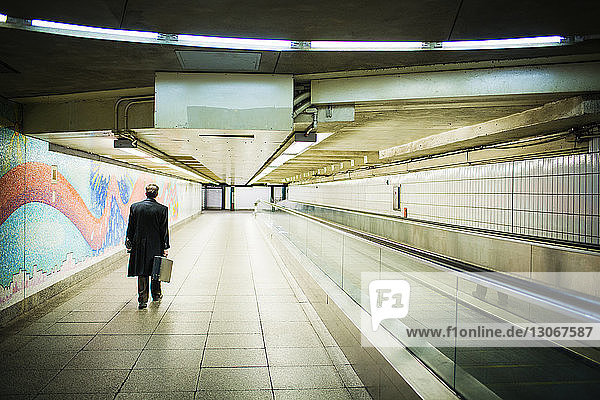 Rückansicht eines in der U-Bahn gehenden Geschäftsmannes mit Aktentasche