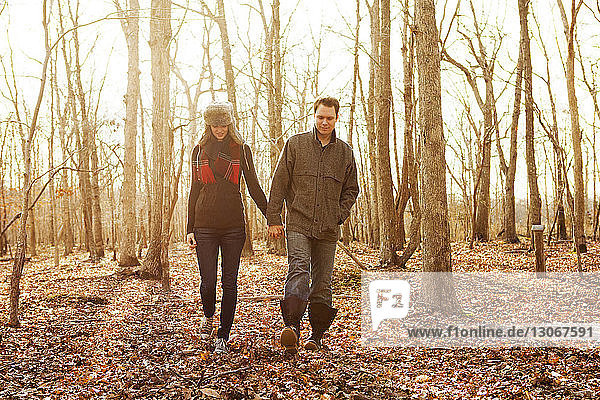 Couple holding hands while walking in forest