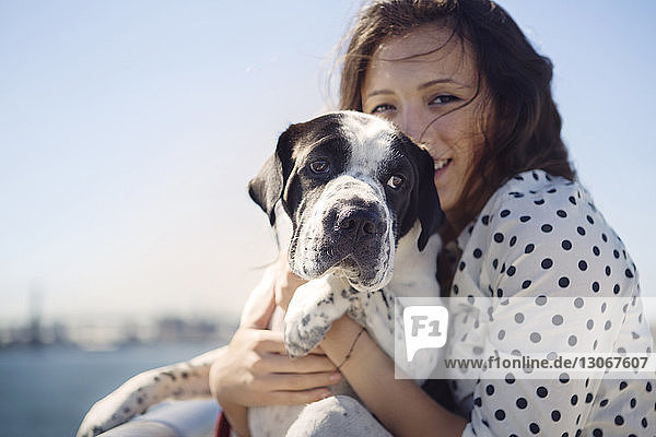 Porträt einer lächelnden Frau mit Hund vor klarem Himmel