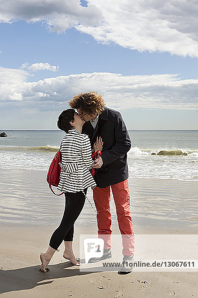 Zärtliches Paar küsst sich  während es am Strand am Ufer steht