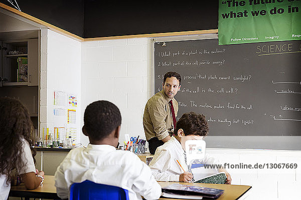 Lehrer betrachtet Schüler während des Unterrichts im naturwissenschaftlichen Klassenzimmer