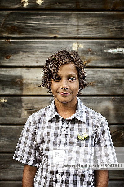 Porträt eines an einer Holzwand stehenden Jungen