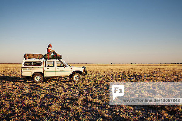 Side view of woman sitting on off-road vehicle at field