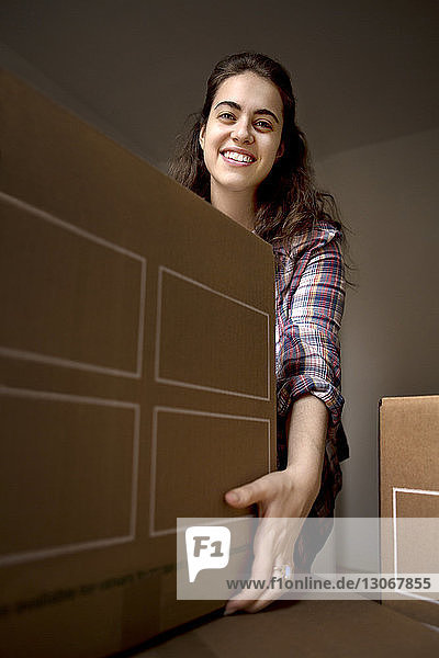 Porträt einer Frau  die zu Hause einen Pappkarton hält