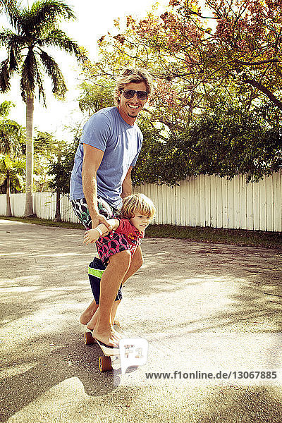 Porträt eines Vaters mit Sohn auf einem Skateboard im Hinterhof stehend