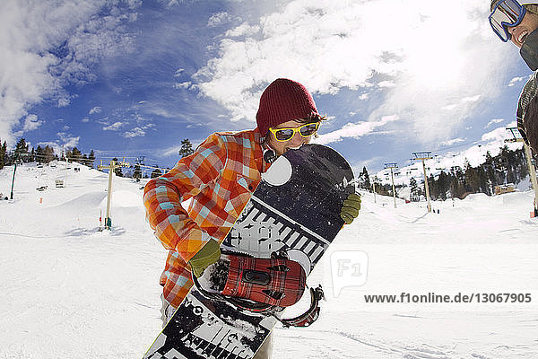 Mann spielt mit Snowboard  während er gegen den Himmel steht