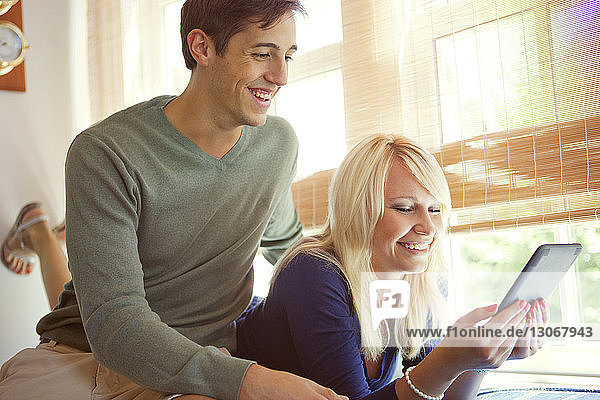 Glückliches Paar schaut sich zu Hause einen Tablet-Computer an