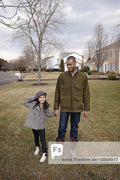 Porträt eines glücklichen Mädchens  das mit seinem Vater im Hinterhof gegen den Himmel steht
