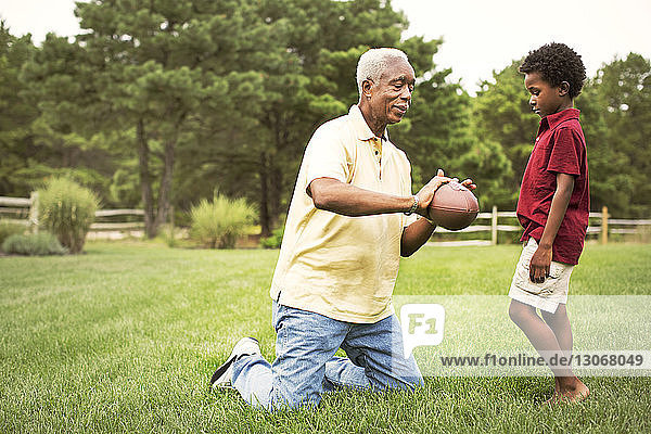 Grandfather and grandson playing football in backyard