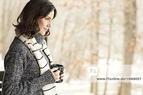 Side view of woman looking away while holding coffee cup