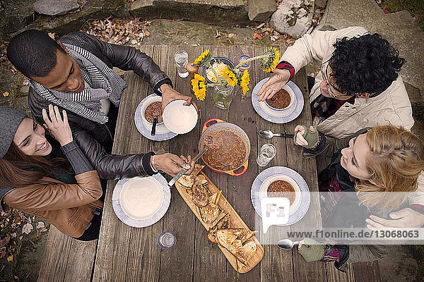 High angle view of friends having food at wooden table outdoors