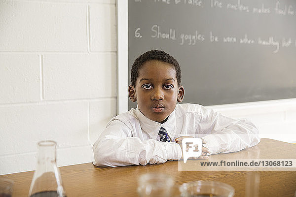 Porträt eines Jungen  der im Labor am Schreibtisch sitzt