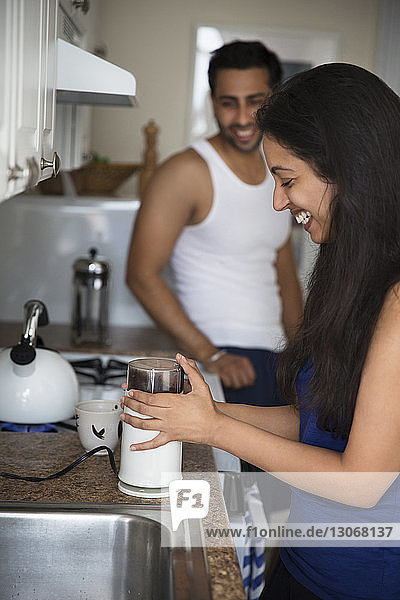 Mann sieht Frau beim Kaffeekochen an  während er in der Küche steht