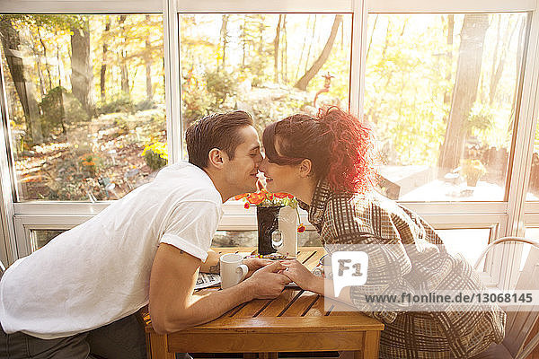 Küssende Paare  die zu Hause am Tisch sitzen